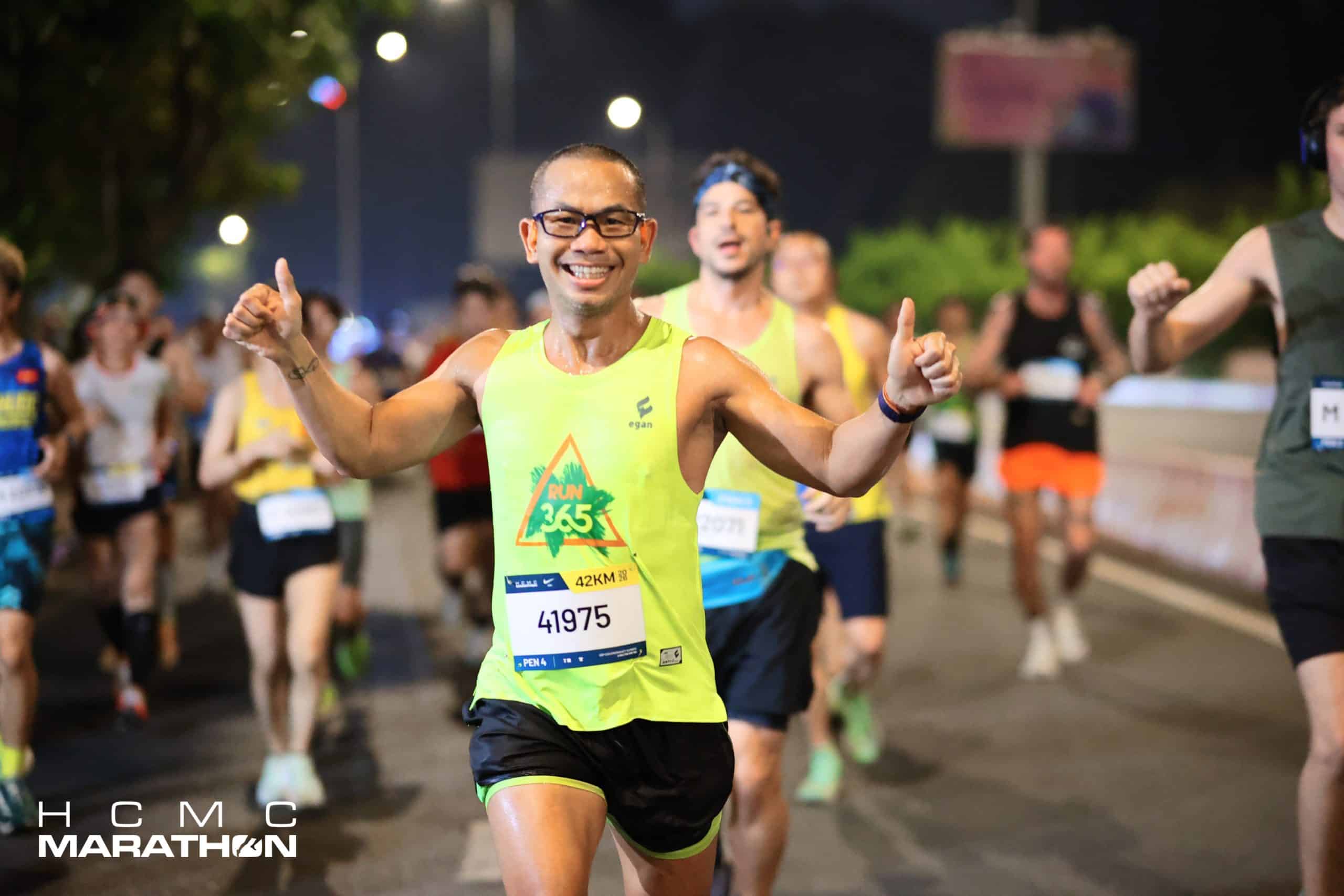 Runner RUN365 dang tay ăn mừng về đích cự ly marathon 42km trong đồng phục singlet solar green