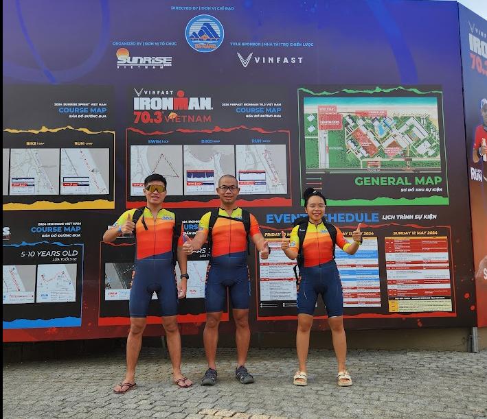 Ba thành viên RUN365 mặc đồ tri-suit đứng xem sơ đồ đường bơi đạp chạy tại khu expo Ironman 70.3 Đà Nẵng
